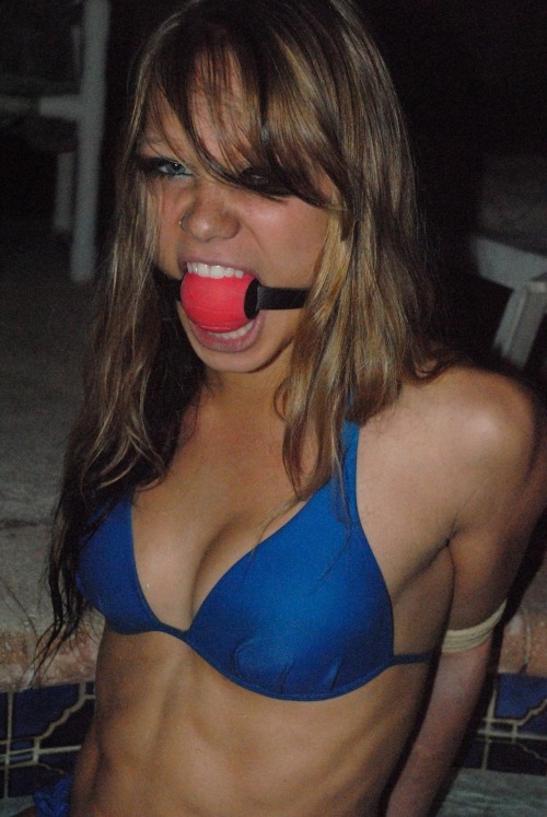 This is my first post. This photo is fantastic. Attractive young girl who seems to be angry behind the gag… which is almost too much for her tiny mouth. Arms bound behind her, bathing suit stretched tight… I can’t wait to see what