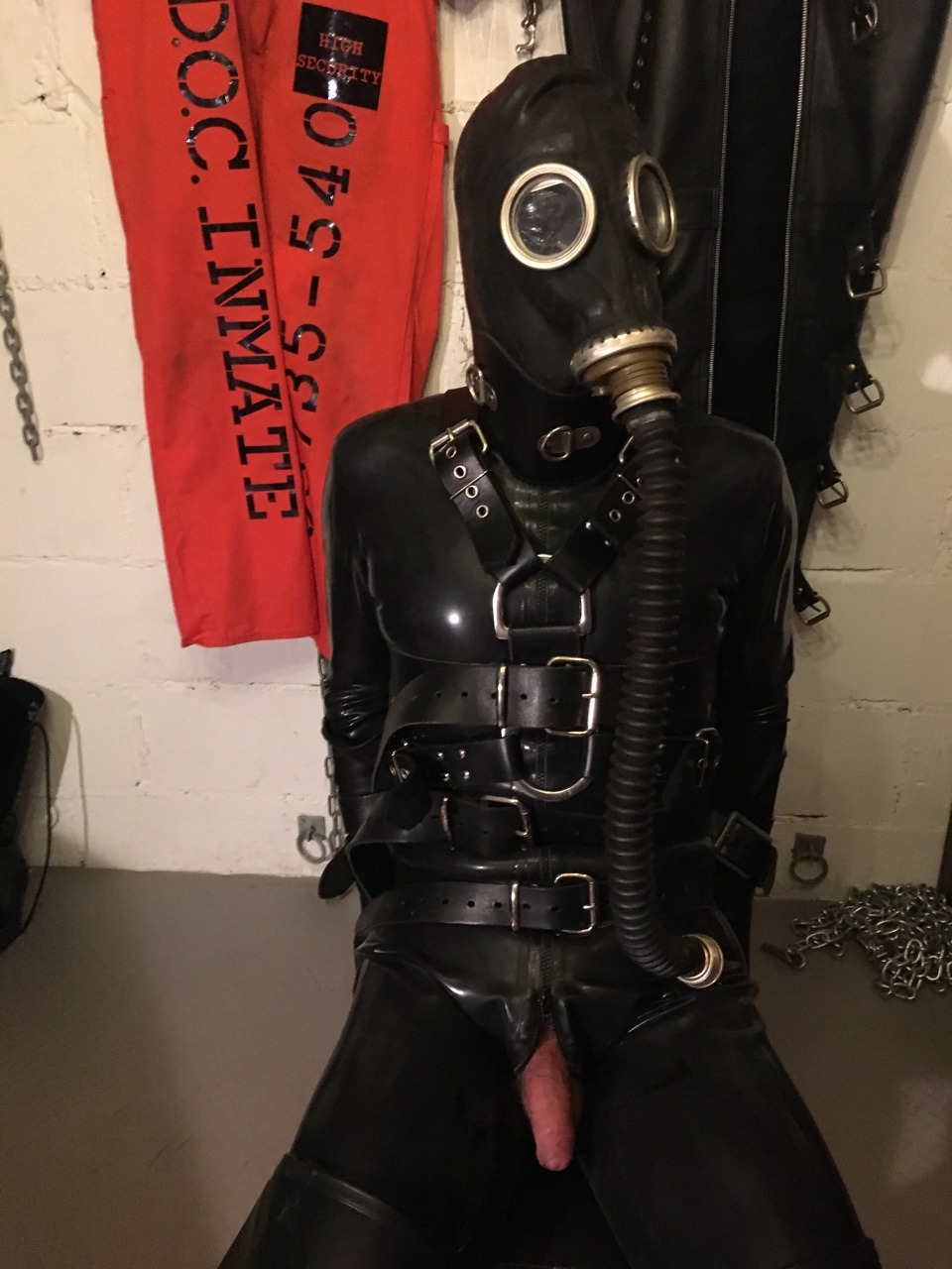 jamesbondagesx:  Rubber gimp strapped to chair, gagged, head mummified, gas masked