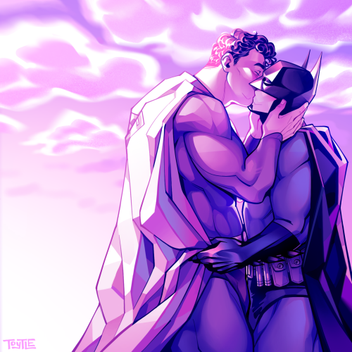 (Late) Valentine’s Day-themed fanart of Superman and Batman kissing. Superman is gently cupping Batman’s face in his hands as Batman pulls Superman in close by the waist of his cape. They are both illuminated by the glow of the pink sunrise behind them.