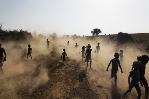 unrar: Kara children kick up dust on their way to participate in a dance, Ethiopia, Randy Olson.