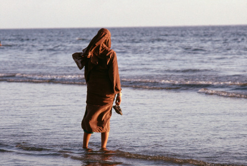 unrar:Karachi, Pakistan. A Muslim woman in nigab looks in the sea 1988, A. Abbas.