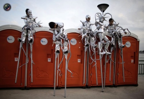 Porn Stiltwalkers rest on a row of port-a-potties photos