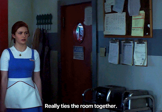 GIF FROM EPISODE 2X09 OF NANCY DREW. NANCY WALKS INTO THE KITCHEN OF THE CLAW. SHE SAYS "REALLY TIES THE ROOM TOGETHER" AS ACE COMES INTO FRAME AND LOOKS AT HER. NANCY COMES TO STAND NEXT TO WHERE HE'S SITTING.