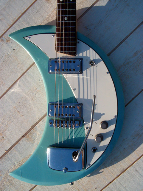 thepit:bleachedvi0let:Crucianelli Spazial 1965 Crecent Moon guitar 🌙[ID:4 pictures of an electric guitar taken from various angles. Its body is in the shape of a crescent. It’s light blue with a white pickguard. It has a vibrator arm/End ID]