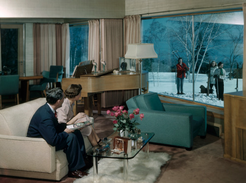 A couple seated in a living room looks out a window at skiers on lawn in Duluth, Minnesota, Septembe