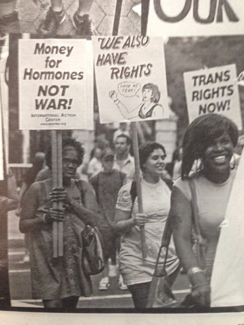 qcrip:[image desc: black and white photo of people holding protest signs reading “Money for Ho