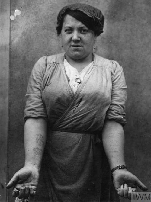 greatwar-1914:A Scottish factory worker shows off her tattoos. Her right arm bears emblems from her 