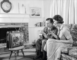 midcenturymodernfreak:  c.1960 Couple enjoying cold brewskis while watching on their deluxe portable black &amp; white Philco TV. - Via