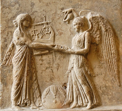 Apollo, with cithara, holds out a phiale (libation dish) to Nike; between them is the omphalos-stone