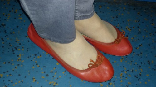 Red leather ballet flats worn with grey skinny jeans