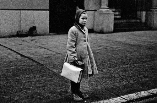 • Men explaining: GirlsGirl with a pointy hood and white schoolbag at the curb, N.Y.C., 1957 - 