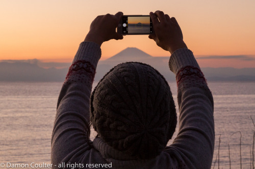 A Japanese woman uses an iphone to take a photo of Mount Fuji during the last sunset of 2016. Muira,