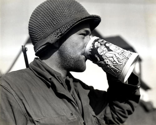 Private Grant Crawford drinking beer from a stein after crossing into Germany, World War II.
