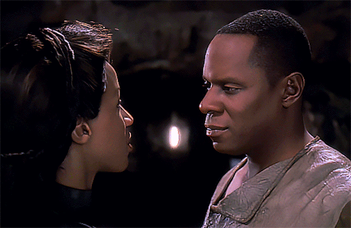 A gif from an earlier DS9 episode, “Through The Looking Glass”. The mirror universe counterpart of Jennifer Sisko leans in to kiss Benjamin on the cheek. Benjamin closes his eyes, overwhelmed.