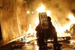 politics-war:  A demonstrator sits in front of a street fire during a demonstration following the grand jury decision in the Ferguson, Missouri shooting of Michael Brown, in Oakland. 