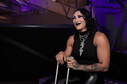A gif of Rhea Ripley. She lifts her arms up and makes a single flapping motion with her hand while saying "yeet."