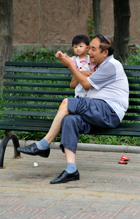 A grandfather enjoying a Saturday afternoon in the park with his grand daughter, Zhengzhou, China.
