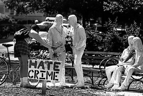 “HATE CRIME,” a passer-by places flowers on George Segal’s “Gay Liberation” after a vandal attacked 