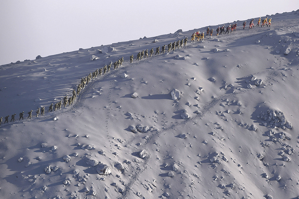 Rescuers walk in line after their search operation near the peak of Mt. Ontake in central Japan. Saturday’s eruption of the volcano was the worst fatal eruption in Japan’s postwar history. (Photo by Kimi Takeuchi/AP via LA Times)