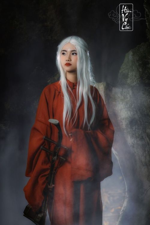 A fantasy photoshoot of a white-haired woman wearing Nguyễn dynasty red áo tấc, reminiscent o
