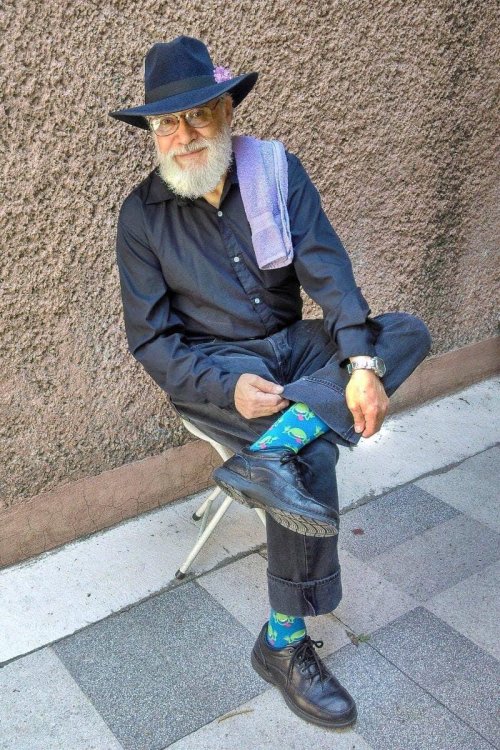 i-ate-nt-dead:Happy Glorious 25th of May and Towel Day! #wearthelilac #gnuterrypratchett #don’tpanic! (image source: visibleprocrast. image description: Sir Terry sits outside with his back to a mortar wall. He has a sprig of lilac tucked into his