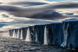 sixpenceee:  “As our ship approached the massive ice cap, I was shocked to see a string of waterfalls that straddled the entire expanse of the melting ice” Nordaustlandet, Svalbard, Norway. Photo by Paul Nicklen.  