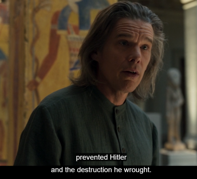 screenshot of a white man with long unwashed hair and a blue shirt. The subtitles say 'prevented Hitler and the destruction he wrought.'