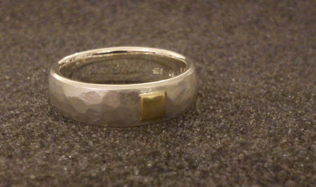 silberner ring mit hammerschlag und goldenem