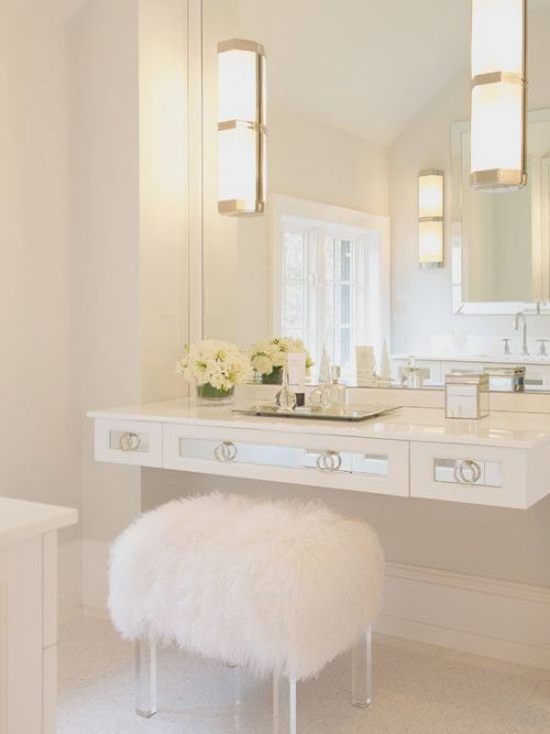 Beautiful bathroom with white mirrored floating vanity accented with white sheepskin vanity stool wi