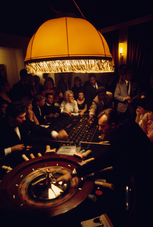 Visitors of diverse nationalities crowd a casino roulette table in Swaziland, 1969.Photograph by Vol