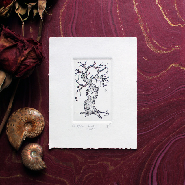 A photo of a 4x5’" intaglio print featuring a linework etching of a bare branched tree with a clock face embedded in the main trunk. Small pocket watches dangle from the branches like fruit.