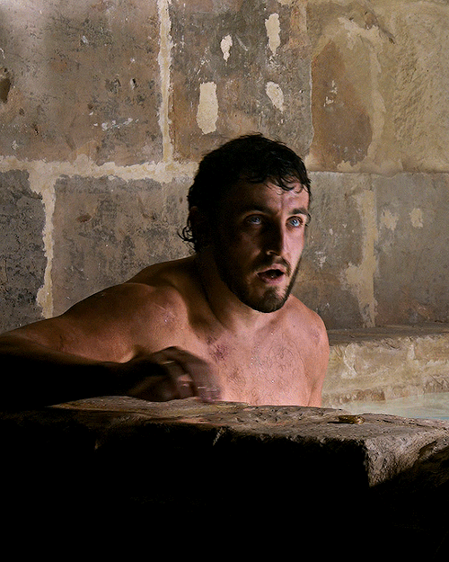 A gifset of Lucius from Gladiator II. A close-up shot of him sitting in a bathhouse. Water is reflecting off of his face and the walls. He leans forward to rest his arm on the side of the bath to listen to Macrinus, who is off-screen.