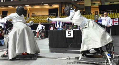 [ID: a wheelchair epee fencer lunging at her opponent.]Shelby Jensen (left) against Camille Chai at 