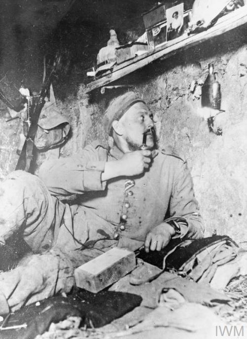 meninroad:© IWM (Q 53666)  A German soldier sits in his dug-out, personal comfort items can be seen 