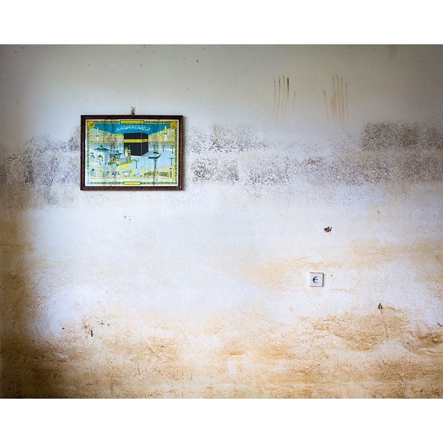 This is my favorite photo from my new series MORE THAN NOTHING. It shows a wall on the second floor of a home that is covered in mold, mud, two handprints, and the sole remaining family possession: a framed poster of the #kaaba in #Mecca where...