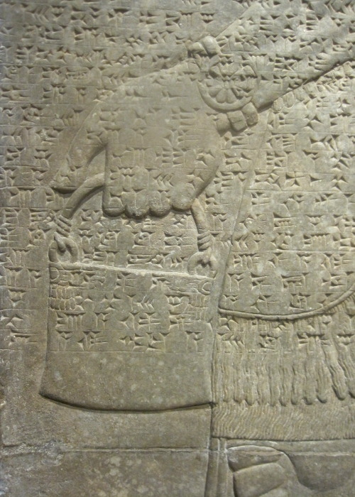 Detail of a bas-relief sculpture depicting a winged guardian spirit with Akkadian Cuneiform writing.
