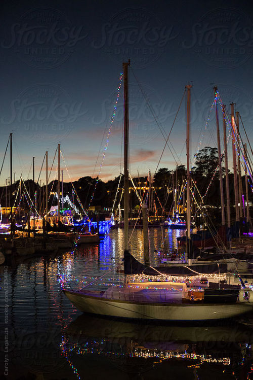 Boats in a harbor decorated with lights for Christmas By catkleinAvailable to license exclusively at