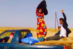 child-of-the-univerrse:  A woman takes off her black garbs to show her colorful dress as she flee ISIS territory.