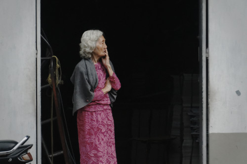 A gray-haired woman looks on worriedly. Bandung, adult photos