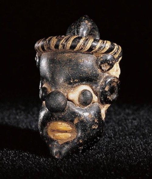 archaicwonder:Phoenician or Carthaginian Core-Formed Glass Pendant in the Form of the Head of an Afr