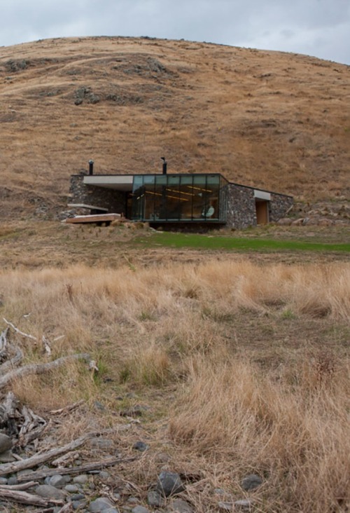 archatlas:    Seascape Retreat    Patterson AssociatesA romantic beachside cottage is set into a rock escarpment in a tiny boulder strewn South Pacific cove. It is a shelter designed as a honeymoon retreat for paying guests consisting of just three rooms,
