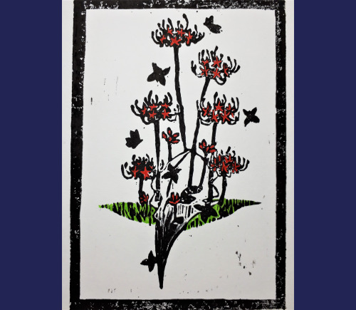 A hand-colored linocut of a crow skull with several red spider lilies growing out of and next to it. There are black butterflies flying around in the scene.