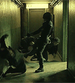 A noticeably tired Matt Murdock doing a spinning wall kick and punching a goon, sending him stumbling through a door way