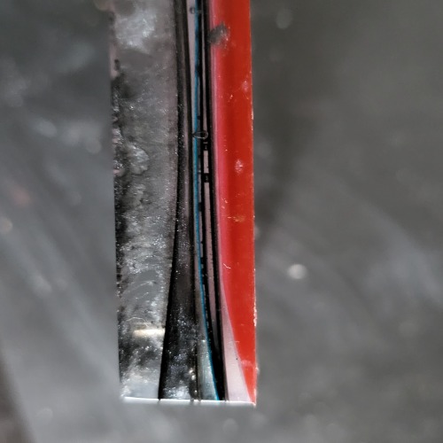 The craft has been pulled out of the silicone mold. A close up view of the sides of the craft shows the layers of paper sitting irregularly and bending between the layers of resin.