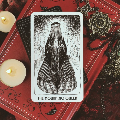 The Mourning Queen: veiled and cocooned in a black dress, she holds a single lit candle.