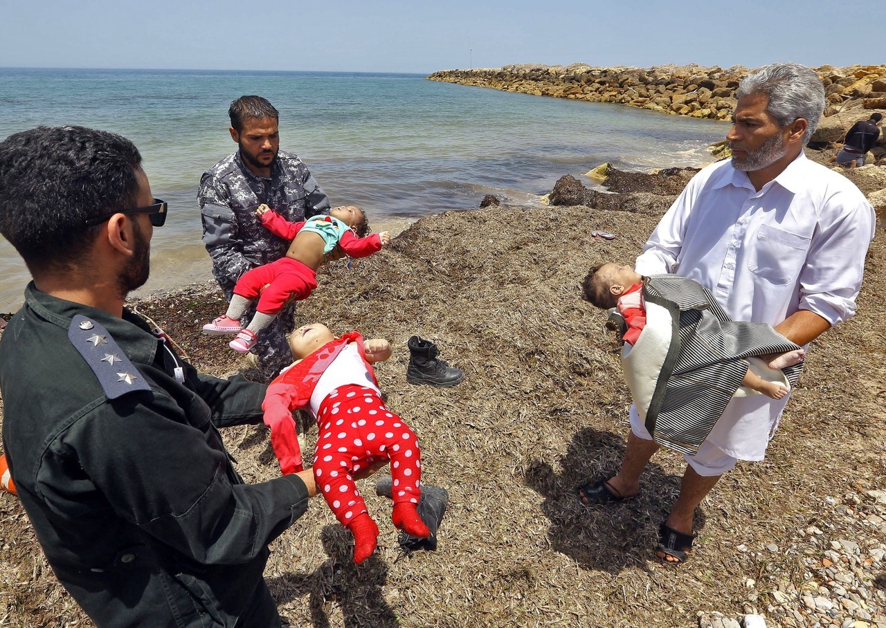 NAUFRAGIO. Miembros de las fuerzas de seguridad libias transportan los cadáveres de bebés mientras los migrantes que sobrevivieron al hundimiento de un bote inflable frente a las costas de Libia son llevados a tierra en al-Hmidiya, al este de la...