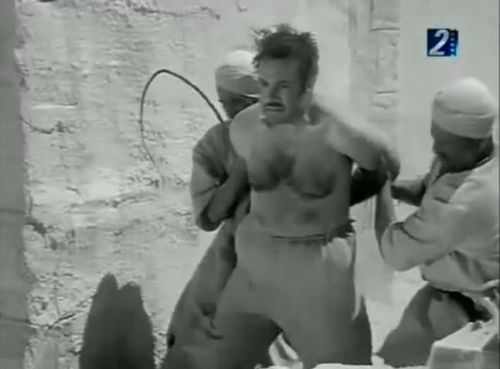Enteqam Al HabibA shirtless, burly, hairy-chested man is put on the ground and whipped with what loo