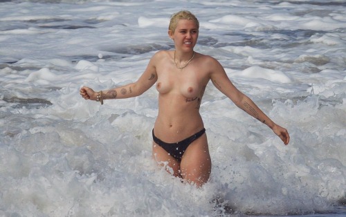 prettylittlerulebreaker:  thenudecity:  Here is Miley Cyrus topless wearing only her bikini bottoms and enjoying the surf at the beach in Hawaii. Cyrus  seems to be going out of her way to show us her naked body in 2015. And  this time around her boobs