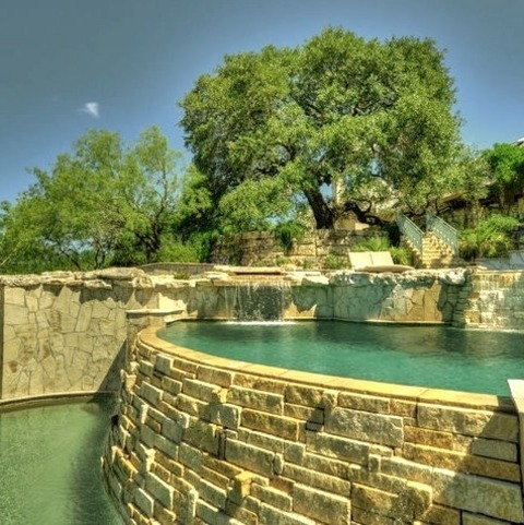 Austin InfinityLarge Backyard Infinity Hot Tub With A Stone Shape And An Island Style.