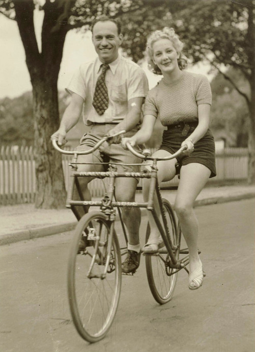 Man and woman on a Malvern Star abreast tandem bicycle, c. 1930s, by Sam Hood by State Library of Ne